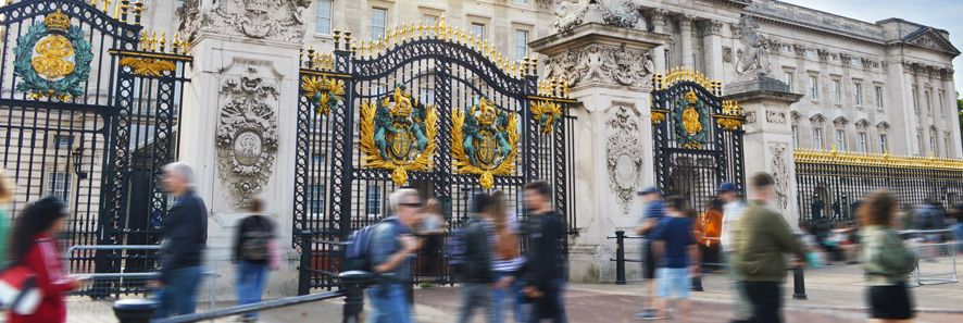 people rushing past the gates of buckingham palac